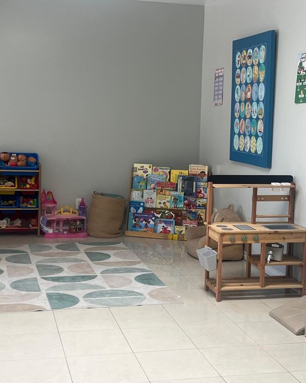 Indoor play area with a wooden play kitchen, toy shelves and picture books