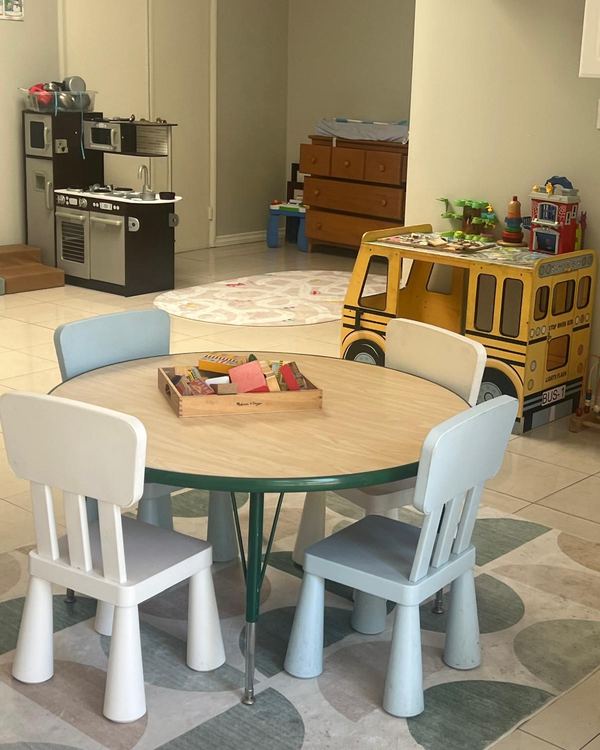 Bright indoor playroom with a round table, child-size chairs and a toy school bus