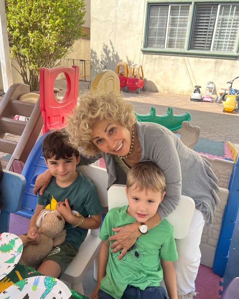 Flora smiling with two children in the play yard
